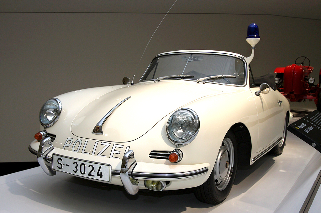 Ganz in Weiß: Polizei-Porsche, dahinter ein roter Porsche-Traktor. 