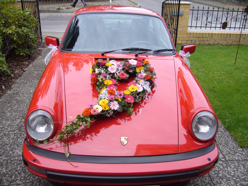 Kampf der Blumenkinder - Porschefahrer geht auf Jungen los. Nur zur Hochzeit darf mal eine Ausnahme gemacht werden: Blumengesteck auf dem Porsche.