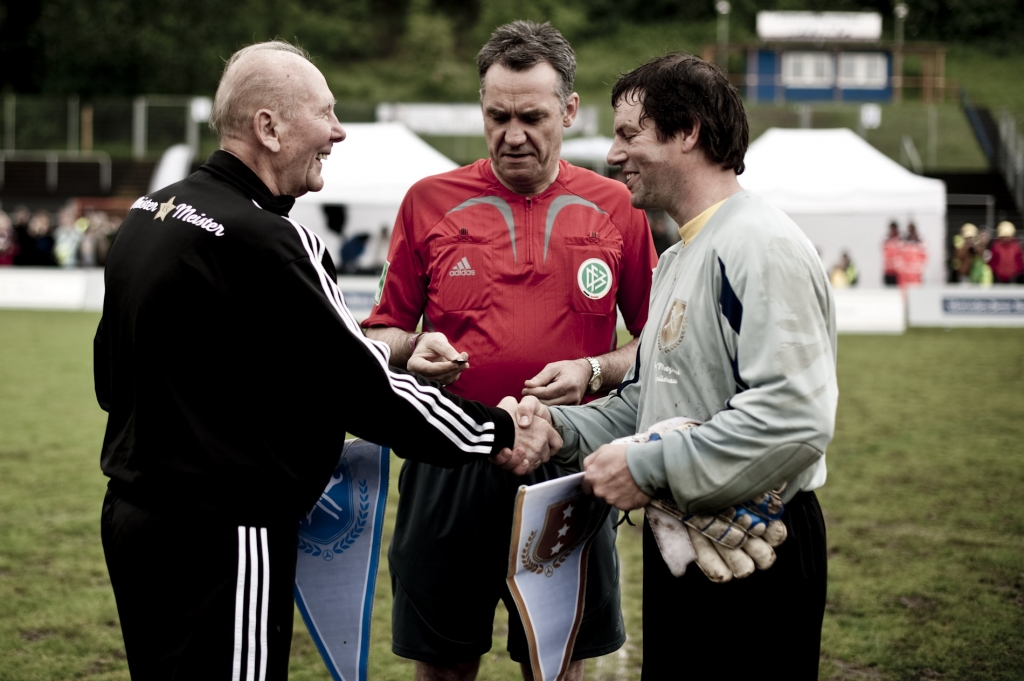 Vor dem Anstoß darf die obligatorische Wimpelübergabe nicht fehlen. Jörg Motzkau (re.), Torhüter des Teams aus Velbert, tauscht mit Horst Eckel (li.) den „Meister vs. Meister“ - Wimpel. 