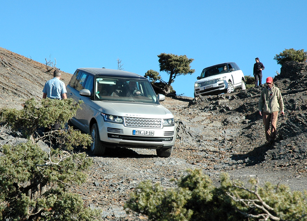 Langsam bewegen sich zwei Range Rover einen steilen Abhang hinunter. 