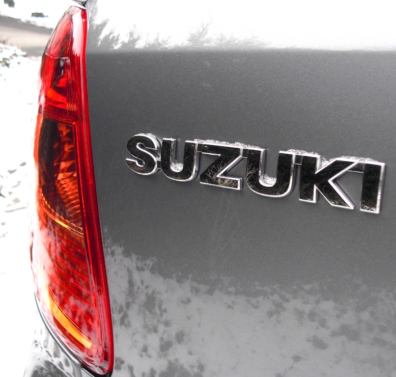 Suzuki SX4: Markenschriftzug neben Leuchteinheit am Heck.
