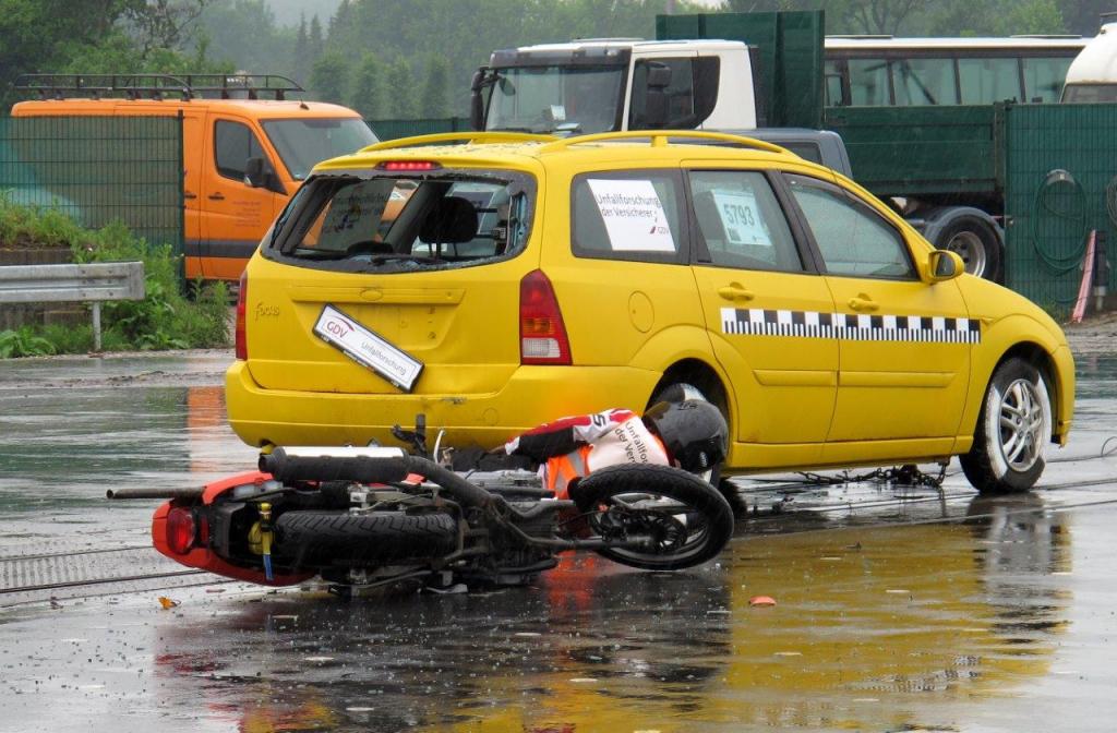 Das Motorrad liegt ein Stück hinter dem gelben Kombi auf der linken Seite, der Dummy ist vom Auto wieder abgeglitten und liegt verkrümmt direkt hinter dem Fahrzeug