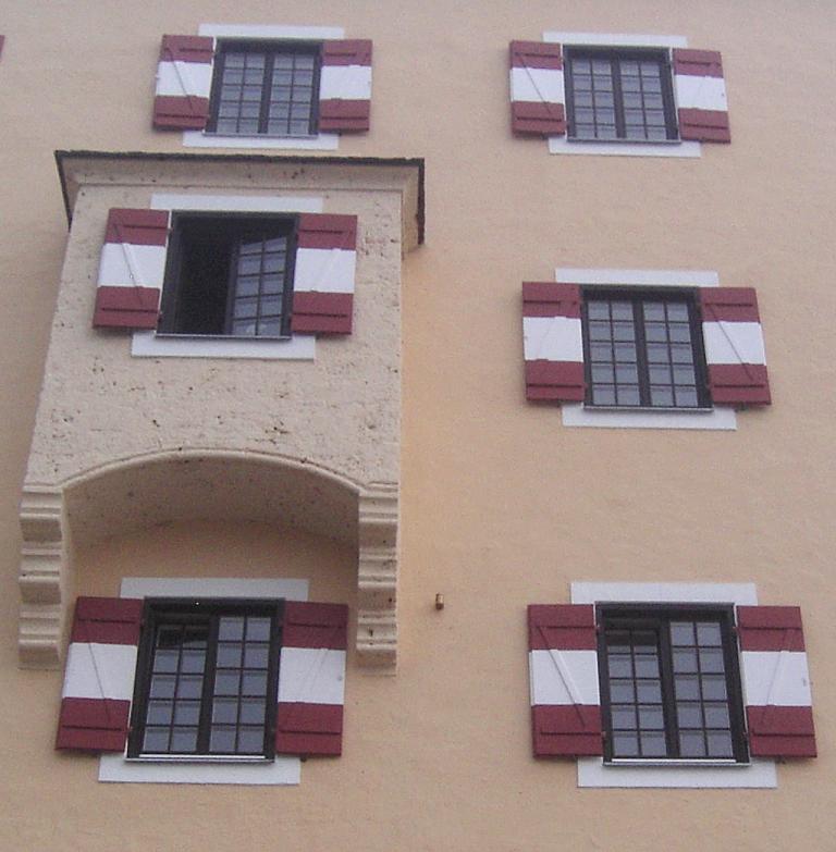 Mit rot-weiß gestreiften Fensterläden: Hausfassade von Schloss Fuschl. 